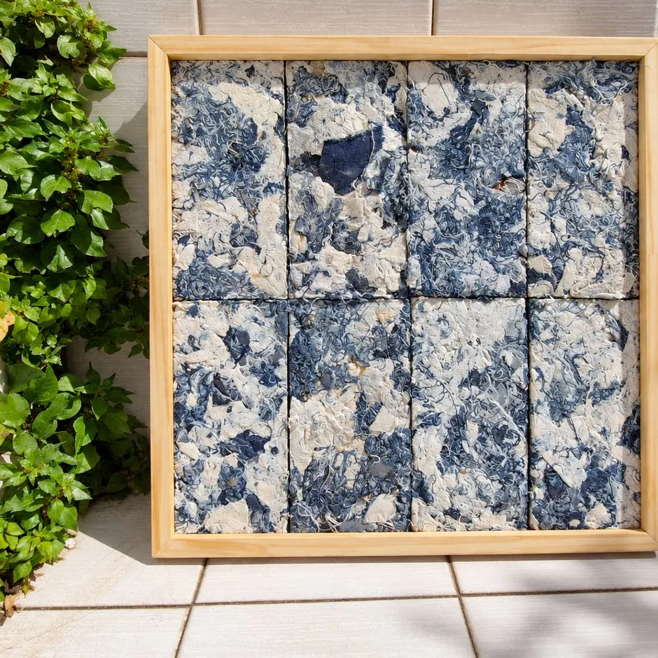 Cuadro de paneles Requecho azul y crema con marco de madera, al sol en un patio con plantas.